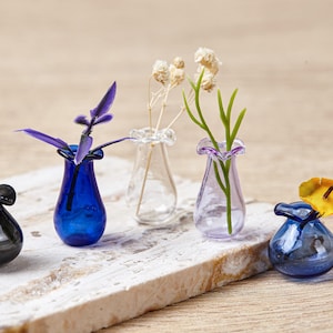 Op de afbeelding: Een witte keramische mok met een zwart handvat en de tekst "But First, Coffee" in een zwarte, vette letter. De mok staat op een wit oppervlak.