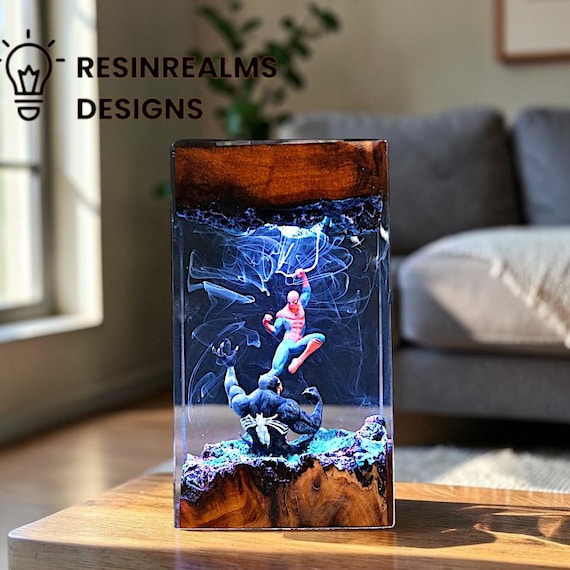 A handcrafted epoxy resin lamp where Spider-Man and Iron Man battle inside a glowing wood slice — it's a diorama nightlight and conversation piece in one.