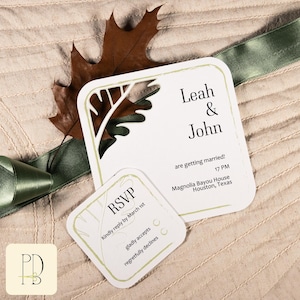 May include: Wedding stationery set with a white invitation card featuring leaf-shaped cutouts and an RSVP card. The invitation states "Leah & John" and wedding details. A brown leaf and green ribbon are included as decoration.
