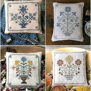 Puede incluir: Cuatro cojines cuadrados decorativos con diseños florales de punto de cruz. Cada cojín presenta una combinación de colores diferente: azul, azul claro, multicolor y marrón. Los arreglos florales están en jarrones, enmarcados por un borde cosido.