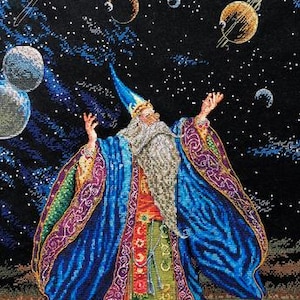 Può includere: Un arazzo dettagliato raffigura un mago con una lunga barba bianca e vesti blu, con le braccia tese verso pianeti e stelle su uno sfondo scuro e cosmico. Le vesti del mago hanno finiture viola e oro. Un'opera d'arte a tema fantasy.