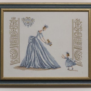 Peut inclure: Une broderie au point de croix encadrée représentant une personne vêtue d'une longue robe bleue fluide face à une plus petite personne portant une robe bleue assortie. L'ensemble est encadré par des piliers dorés et un motif floral bleu et or.