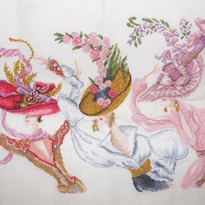 May include: Cross-stitch artwork featuring three figures wearing elaborate hats adorned with flowers and ribbons. The hats are in shades of red, gold, and pink, with the figures in white and pink clothing. The artwork is on a white background.