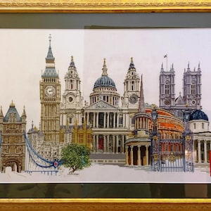 May include: Framed artwork showing a detailed illustration of London landmarks, including Big Ben, St. Paul's Cathedral, and the Houses of Parliament. The artwork is framed in a gold-coloured frame and features a red telephone box.