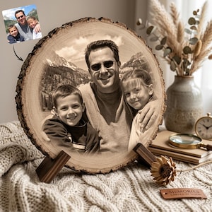 May include: A circular wood slice featuring a laser-engraved monochrome photograph of a man, a boy, and a girl. The wood slice has natural bark edges and is supported by two dark wooden stands. A small rectangular tag labeled MEMORIES CARVED IN WOOD is included.