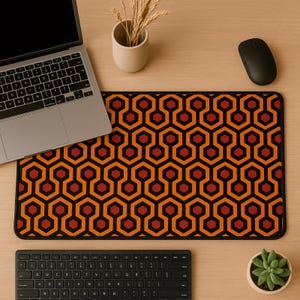 Könnte beinhalten: Rechteckiges Mauspad mit schwarzem Rand und einem sich wiederholenden geometrischen Muster in Orange, Rot und Schwarz. Das Muster besteht aus miteinander verbundenen Sechsecken und Achtecken. Ein Laptop, eine Tastatur und eine Maus liegen auf der Holzoberfläche.