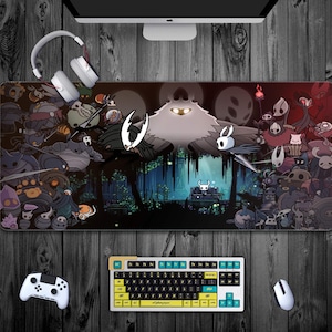 以下が含まれることがあります： ビデオゲームのキャラクターが描かれた、長方形のマウスパッド。グレー、黒、白の色合いの様々なキャラクターが、暗い背景に描かれています。キーボード、マウス、コントローラーが見えます。