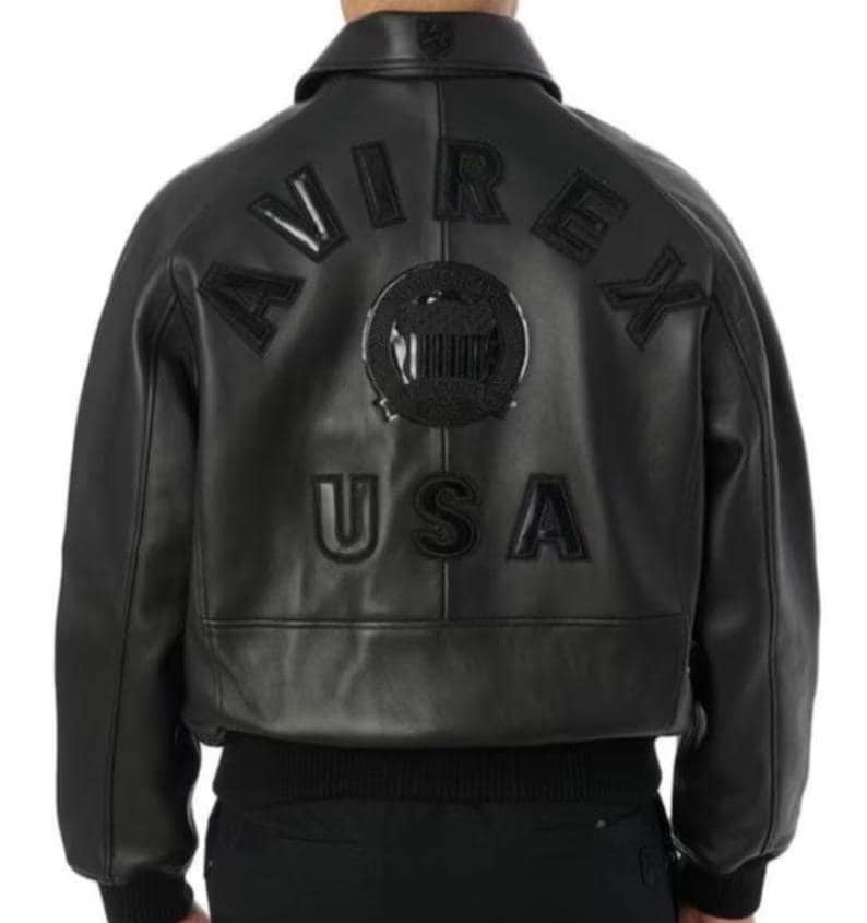 May include: Black leather bomber jacket featuring the word "AVIREX" arched across the back, above a circular emblem and the word "USA". The jacket has a ribbed hem and cuffs, and a classic collar.