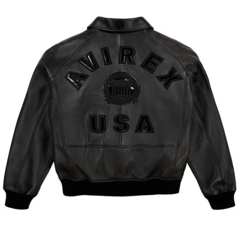 May include: Black leather jacket featuring the word "AVIREX" arched across the back, a circular emblem, and the word "USA". The jacket has a classic bomber style with a ribbed hem and cuffs.