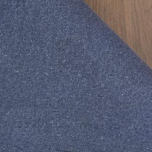 May include: A piece of blue fabric with a visible woven texture. The material features a consistent deep blue color throughout, displaying a tight weave pattern with subtle variations in the thread density across the surface of the textile.