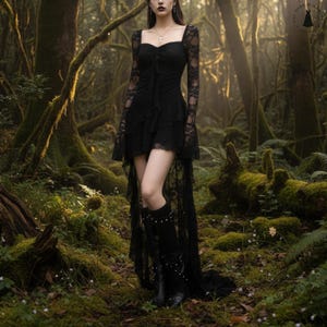 Może przedstawiać: Czarna gotycka sukienka z kwadratowym dekoltem, długimi koronkowymi rękawami i warstwową spódnicą. Sukienka ma asymetryczny dół z długim koronkowym trenem. Modelka ma na sobie czarne kozaki do kolan ze srebrnymi ćwiekami. Tło to las.