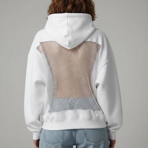 K&ouml;nnte beinhalten: Wei&szlig;er Kapuzenpullover mit Mesh-R&uuml;ckenteil. Der Kapuzenpullover hat eine Kapuze mit Kordelzug, lange &Auml;rmel und eine lockere Passform. Das Mesh-Panel ist hellbraun und der Hoodie wird mit hellblauen Jeans kombiniert.