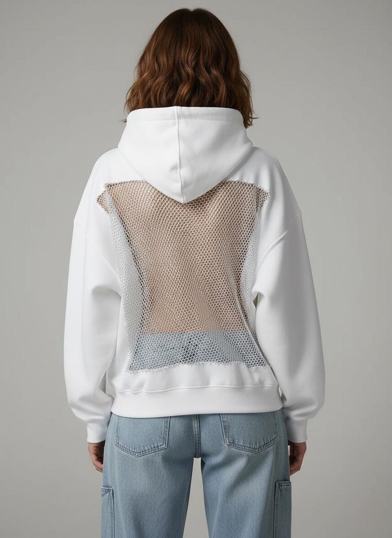 K&ouml;nnte beinhalten: Wei&szlig;er Kapuzenpullover mit Mesh-R&uuml;ckenteil. Der Kapuzenpullover hat eine Kapuze mit Kordelzug, lange &Auml;rmel und eine lockere Passform. Das Mesh-Panel ist hellbraun und der Hoodie wird mit hellblauen Jeans kombiniert.