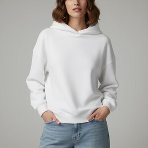 K&ouml;nnte beinhalten: Ein wei&szlig;er Kapuzenpullover mit Kordelzug und langen &Auml;rmeln. Der Pullover ist aus einem weichen Material gefertigt und wird mit hellblauen Jeans kombiniert. Das Model tr&auml;gt den Pullover und die Jeans.