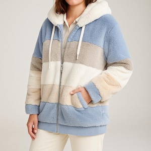 May include: A hooded zip-up jacket with a faux fur texture. The jacket features horizontal stripes in shades of blue, beige, white, and tan. It has a drawstring hood and two front pockets. The jacket is designed for warmth and comfort.