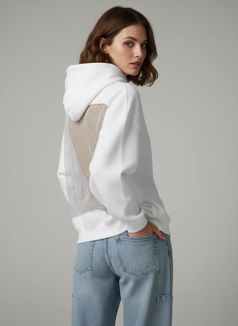 K&ouml;nnte beinhalten: Wei&szlig;er Kapuzenpullover mit Mesh-R&uuml;ckenteil. Der Hoodie hat eine Kapuze mit Kordelzug und lange &Auml;rmel. Das Model tr&auml;gt hellblaue Jeans. Der Mesh-R&uuml;cken verleiht dem l&auml;ssigen Sweatshirt ein einzigartiges Designelement.