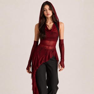 Op de afbeelding: Een mouwloze donkerrode top met capuchon van transparante mesh-stof met een subtiel zwart patroon, een colhals en een asymmetrische zoom met ruches. Het kledingstuk bevat bijpassende lange vingerloze handschoenen van transparante mesh-stof.
