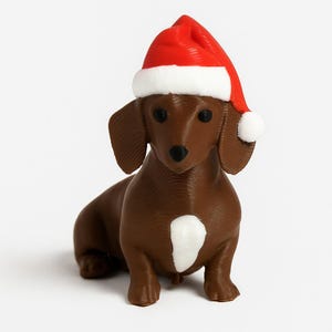 May include: A brown dachshund figurine wearing a red and white Santa hat with a white pom-pom. The dog has a white patch on its chest and a black nose and eyes. The figurine is a festive holiday decoration.