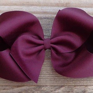 May include: A large burgundy bow made from grosgrain ribbon. The bow is tied with a single loop in the center.