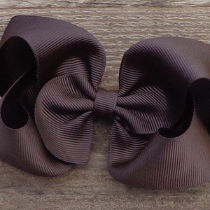 May include: A large brown hair bow made from grosgrain ribbon. The bow is tied in a classic style with two loops and a center knot.