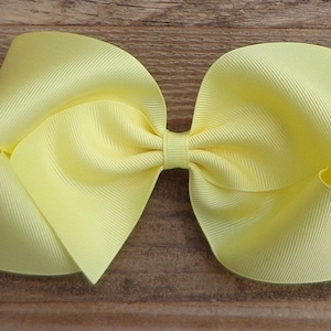May include: A large, bright yellow bow made from grosgrain ribbon. The bow is tied in a classic style with a center loop.