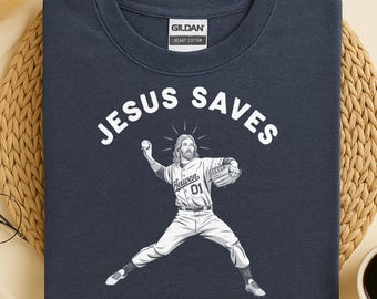 May include: Navy blue sweatshirt with the words "JESUS SAVES" in white block letters. A graphic of Jesus in a baseball uniform pitching a ball is below the text. The sweatshirt is made of heavy cotton.