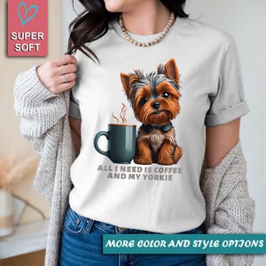 May include: White t-shirt featuring a Yorkshire Terrier illustration with a coffee mug. The text reads "ALL I NEED IS COFFEE AND MY YORKIE". The shirt has rolled-up sleeves and is labeled "SUPER SOFT".