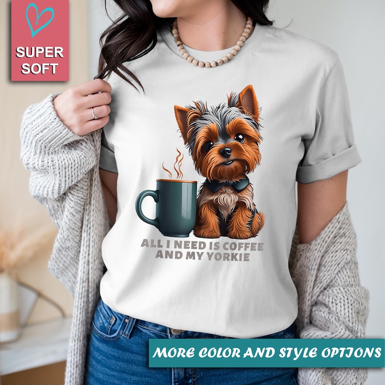 May include: White t-shirt featuring a Yorkshire Terrier illustration with a coffee mug. The text reads "ALL I NEED IS COFFEE AND MY YORKIE". The shirt has rolled-up sleeves and is labeled "SUPER SOFT".
