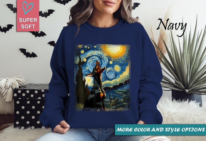 Puede incluir: Sudadera azul marino con un perro aullando a la luna, inspirada en "La noche estrellada" de Van Gogh. La obra de arte est&aacute; enmarcada. Las palabras "Super Soft" est&aacute;n en un cuadrado rosa. Las palabras "More color and style options" est&aacute;n en un rect&aacute;ngulo verde.