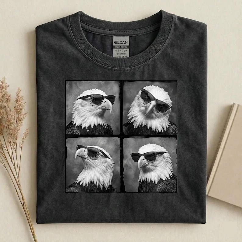 May include: Dark gray t-shirt featuring a square graphic of four black and white images of an eagle wearing sunglasses. The shirt is made of a soft, heavy cotton material.
