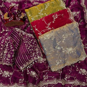 May include: A collection of richly embroidered textiles in shades of purple, red, yellow, and gray. The fabrics feature intricate floral patterns and gold embellishments, suggesting a luxurious aesthetic. The image showcases a variety of textures and designs.