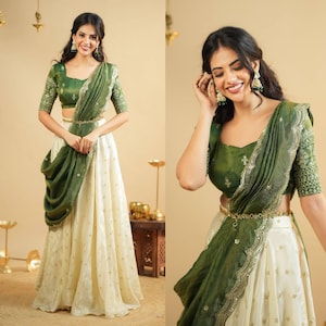 Puede incluir: Un atuendo tradicional indio con una blusa verde con mangas bordadas y una bufanda a juego. El atuendo incluye una falda color crema con detalles dorados y un cinturón dorado. El conjunto es elegante y festivo.