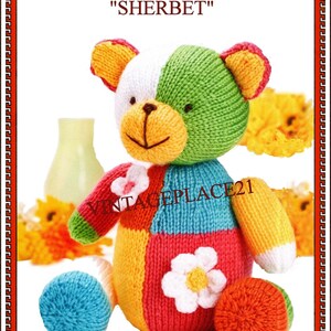 Puede incluir: Un oso de peluche tejido multicolor llamado Sherbet con un diseño de parches en blanco, verde, amarillo, azul, rojo y naranja. El oso presenta una aplicación de flor blanca en el torso y una flor más pequeña en el hombro. El texto dice DIGITAL DOWNLOAD CUDDLY TEDDY BEAR SHERBET, VINTAGEPLACE21 y FOUROAKS12 PATTERNS.