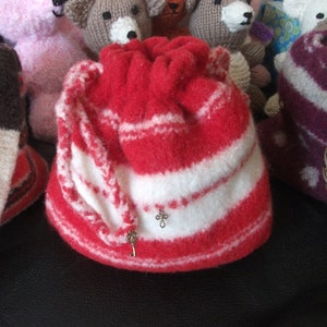 May include: A red and white striped knitted drawstring bag with a key charm. The bag is made of soft, fluffy yarn and has a gathered top.