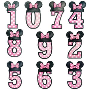 May include: A collection of nine number designs, each featuring a black mouse ear silhouette with a pink bow. The numbers are pink with white polka dots and outlined in black. The numbers are 0, 1, 2, 3, 4, 5, 6, 7, 8, and 9.