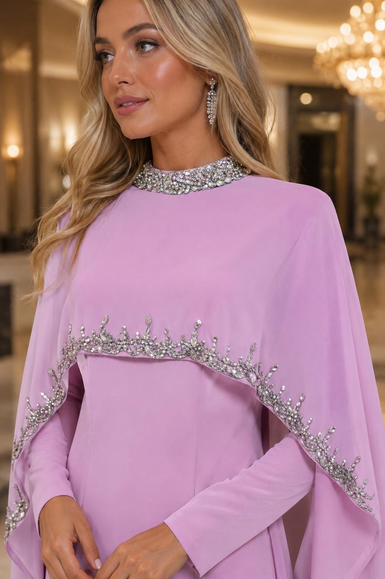 May include: A light purple long-sleeved dress featuring a high neckline adorned with clear crystals and a matching cape overlay. The cape is embellished with a decorative border of silver-toned crystals and beads along the scalloped lower edge.