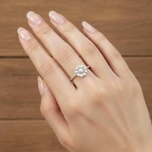 Könnte beinhalten: Ein silberner Ring mit einem Gänseblümchen-Blüten-Design. Der Ring hat ein schmales Band und die Blume hat detaillierte Blütenblätter und ein strukturiertes Zentrum. Der Ring wird an einem Finger getragen und zeigt die filigrane Handwerkskunst und das florale Thema des Schmucks.