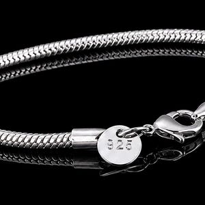 May include: A silver-coloured snake chain bracelet featuring a polished finish and a lobster claw clasp. A small, round metal tag is attached near the clasp, clearly engraved with the number 925, indicating the sterling silver composition.