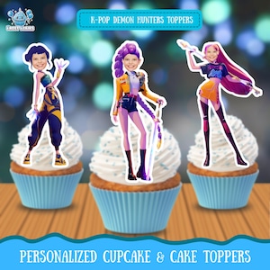 May include: Three cupcakes with white frosting and personalized K-Pop Demon Hunters toppers. The toppers feature cartoon illustrations of people in colorful outfits. The cupcakes sit on a wooden surface with a blue banner that reads "PERSONALIZED CUPCAKE & CAKE TOPPERS."