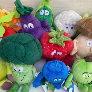 Può includere: Una collezione di peluche di verdure e frutta, tra cui un broccolo, una fragola e un mirtillo. Ogni giocattolo ha una faccia sorridente ed è realizzato in morbido tessuto colorato. I giocattoli sono progettati per assomigliare a vari tipi di prodotti.