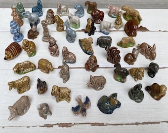 Può includere: Una vasta collezione di statuette di animali in miniatura in ceramica di vari colori e pose, tra cui un riccio, una tigre, un coniglio, una mucca e un uccello. Queste piccole sculture smaltate presentano texture dettagliate e varie specie animali.