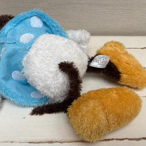 May include: A collection of plush toy parts, including a white, fluffy mushroom cap with a brown stem, a light blue piece with white polka dots, and two orange-brown pieces. The toys are made of soft, fuzzy material.