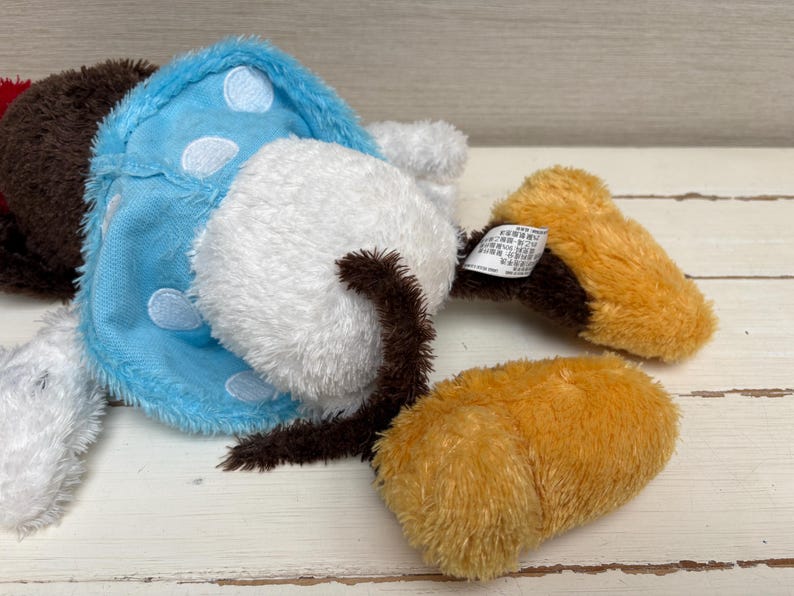 May include: A collection of plush toy parts, including a white, fluffy mushroom cap with a brown stem, a light blue piece with white polka dots, and two orange-brown pieces. The toys are made of soft, fuzzy material.