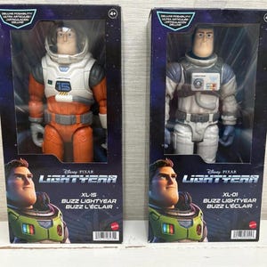 May include: Two boxed Disney Pixar Lightyear action figures. One figure is orange and white, labeled XL-15. The other is white and grey, labeled XL-01. Both figures are in clear plastic packaging with the words "Lightyear" and "Buzz L'&Eacute;clair".