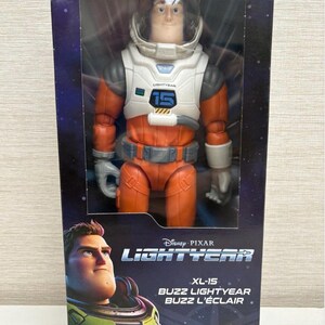 May include: Buzz Lightyear action figure in a box. The figure is wearing an orange and white spacesuit with a clear helmet. The box features the Disney Pixar Lightyear logo and the text "XL-15 Buzz Lightyear Buzz L'&Eacute;clair".
