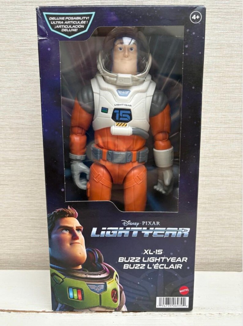 May include: Buzz Lightyear action figure in a box. The figure is wearing an orange and white spacesuit with a clear helmet. The box features the Disney Pixar Lightyear logo and the text "XL-15 Buzz Lightyear Buzz L'&Eacute;clair".