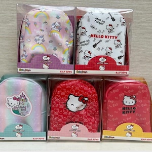 May include: Five small, boxed backpacks with Hello Kitty designs. The backpacks display patterns like rainbows, musical notes, and Hello Kitty faces. Each backpack is packaged in a clear plastic box, with the text "KAP TOYS" and "Little Babe".