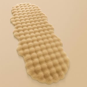 May include: A beige, irregularly shaped rug with a textured, bubble-like pattern. The rug has a soft, plush appearance and is designed to provide comfort and style to any room. The rug's neutral color makes it versatile for various interior design schemes.