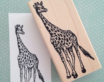 May include: A wooden stamp with a black and white illustration of a giraffe. The giraffe is standing on all four legs with its head held high. The stamp is on a light blue background with white polka dots.