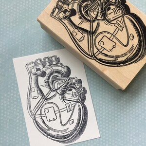 May include: A black and white illustration of a stylized heart with intricate internal workings, printed on a wooden block.